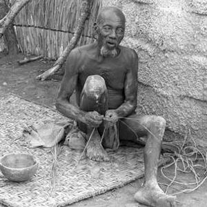 Elderly man sitting with twine in Nigeria, 1967-1969